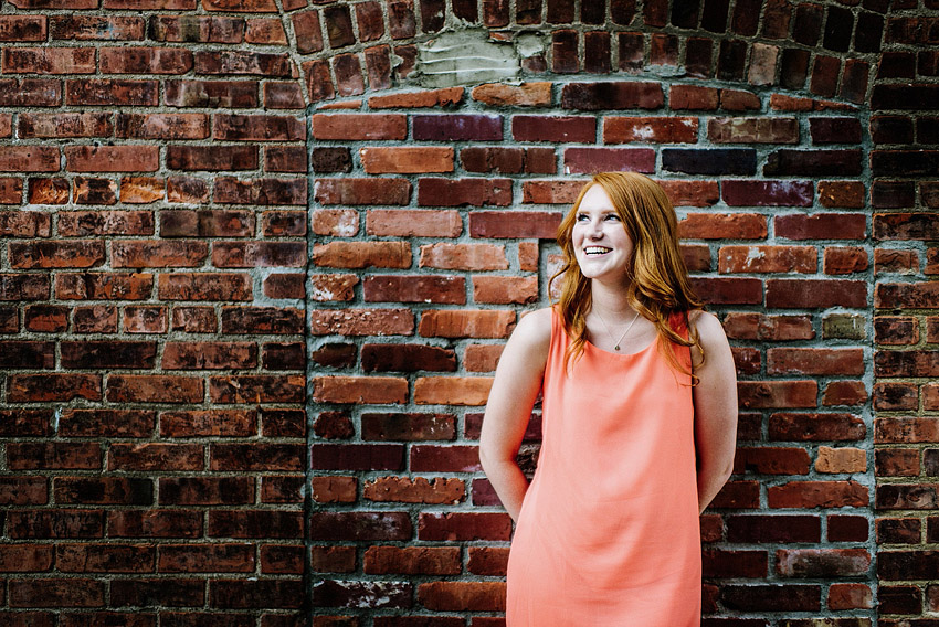 smiling in front of a brick wall