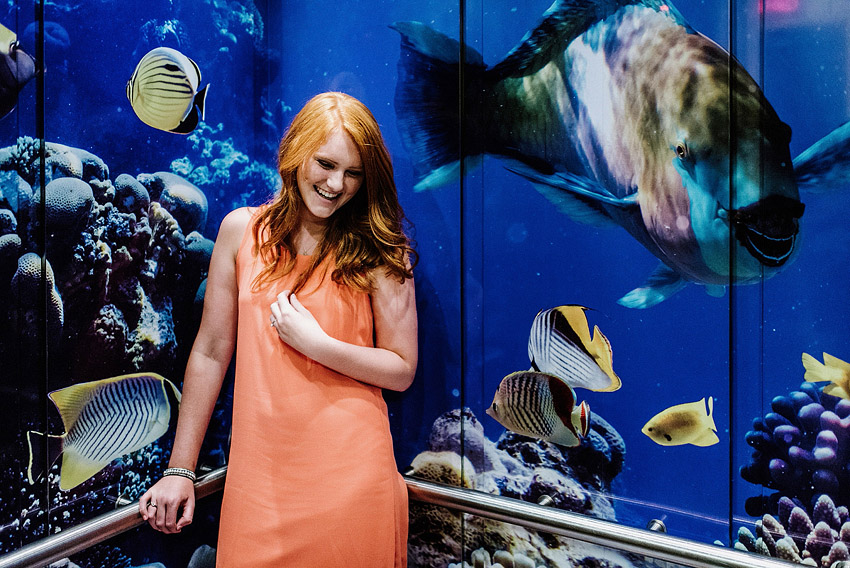 girl smiling in front of fish wallpaper