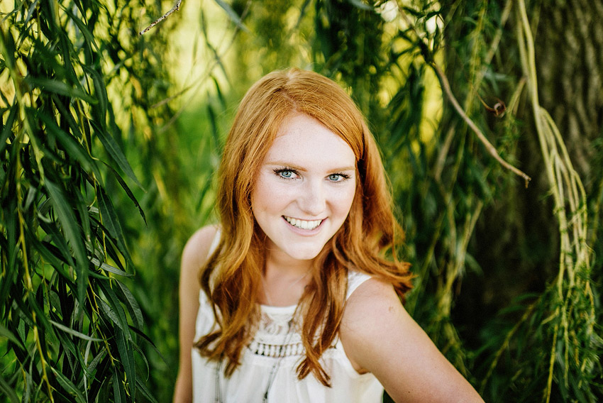 senior girl smiling under a willow tree