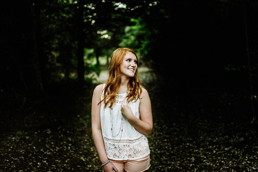 redhead senior girl standing in the woods