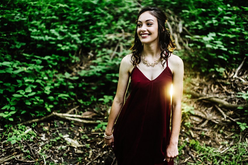 smiling girl in the woods with light behind her