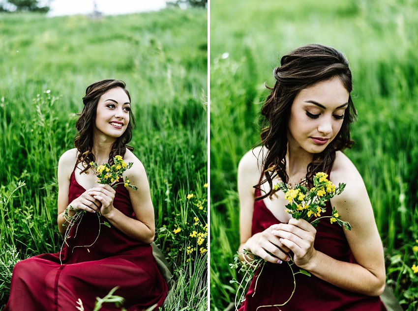 a girl in a red dress sitting in a field holding flowers