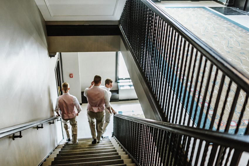 groomsmen walking down the hotel stairwell