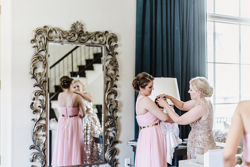 baby getting her hair adjusted by bridesmaids
