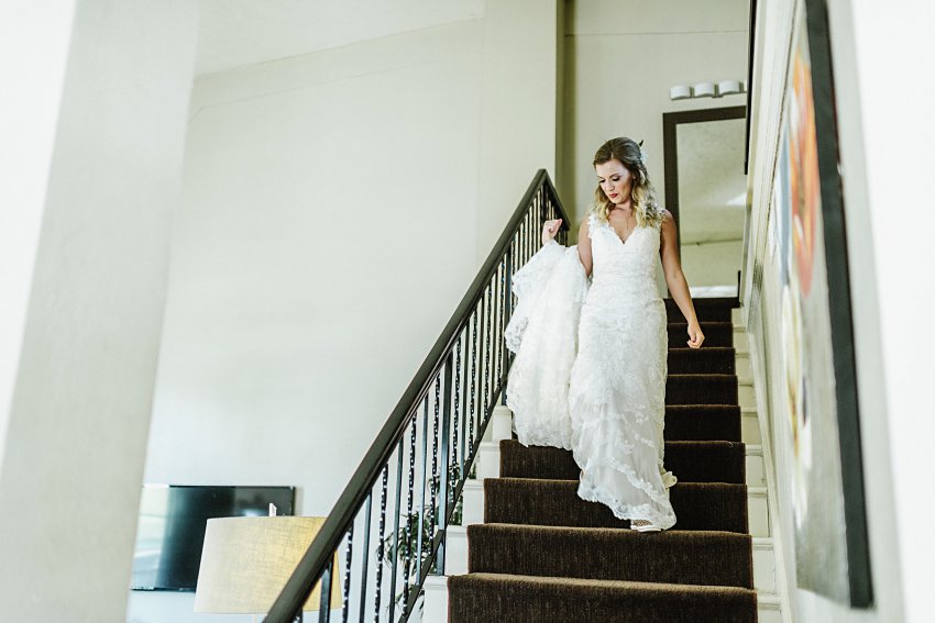 the bride walking down the stairs after putting on her dress