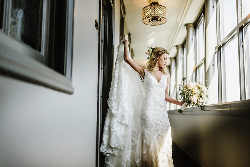 the bride standing in a hallway looking down at her flowers