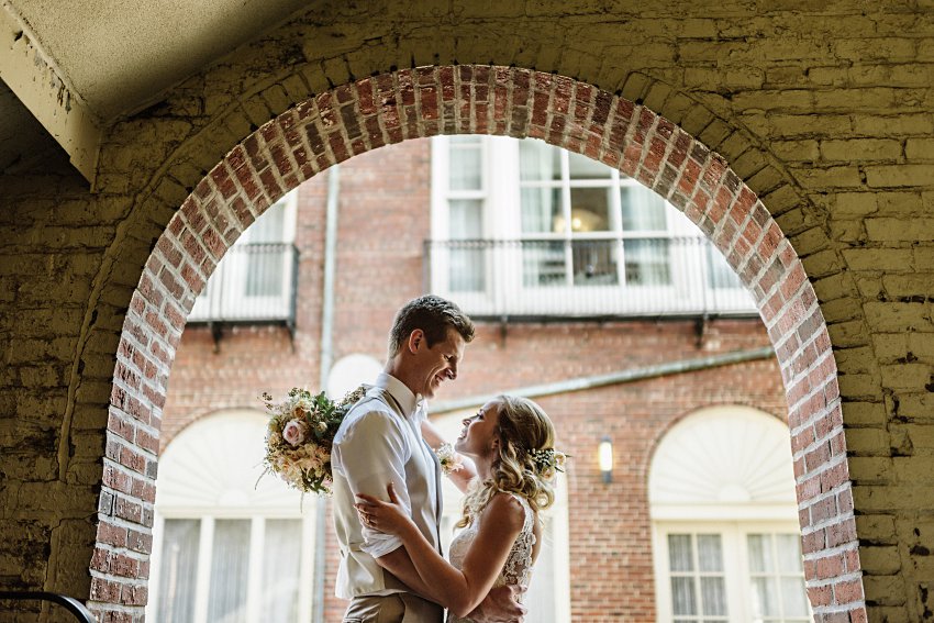 the bride and groom smiling at each other under a brick arch