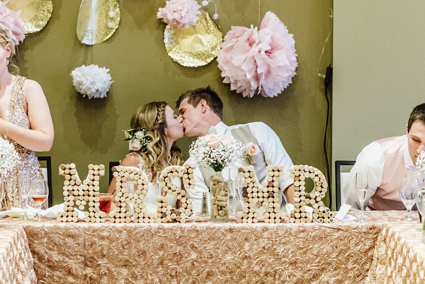 the bride and groom kissing each other at the head table