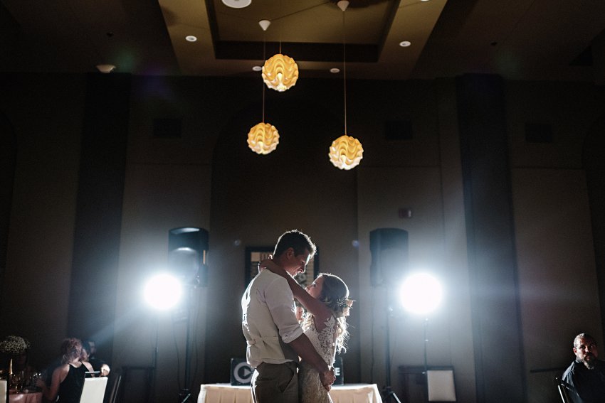 a bride and groom having their first dance in the spotlights