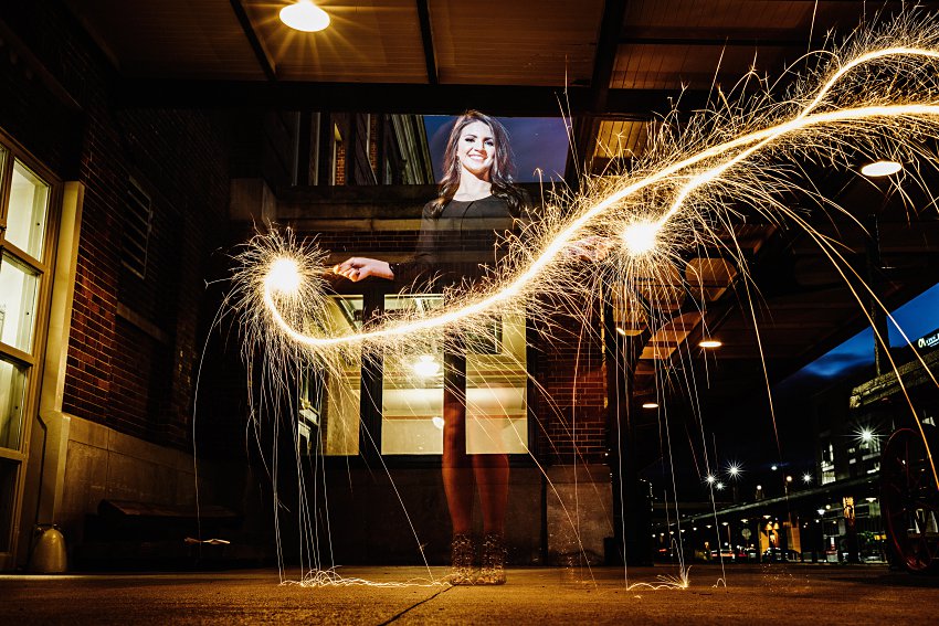 girl in a black dress waving sparklers around as they make light streaks