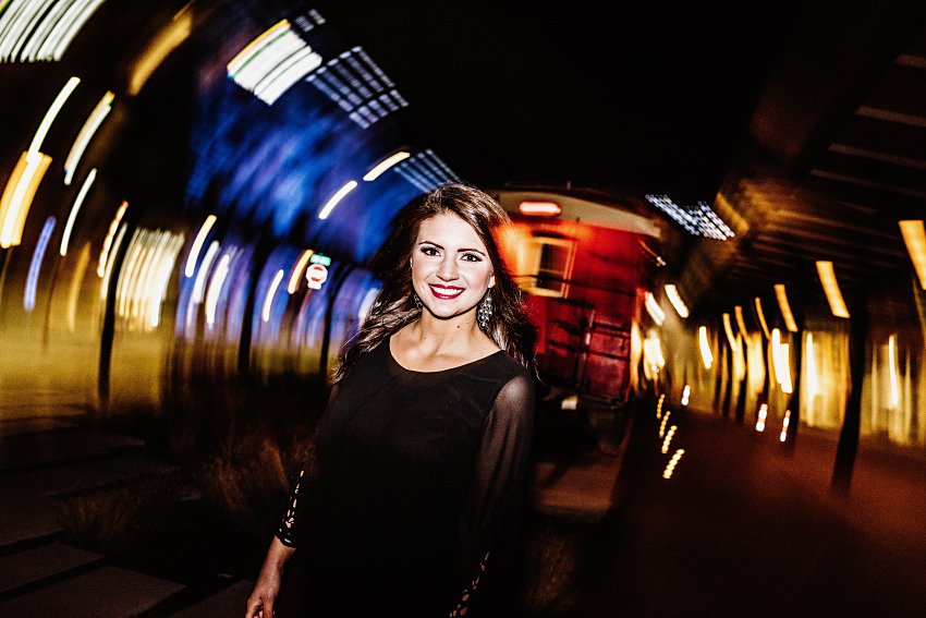 girl in a black dress walking with blurred lights all around her