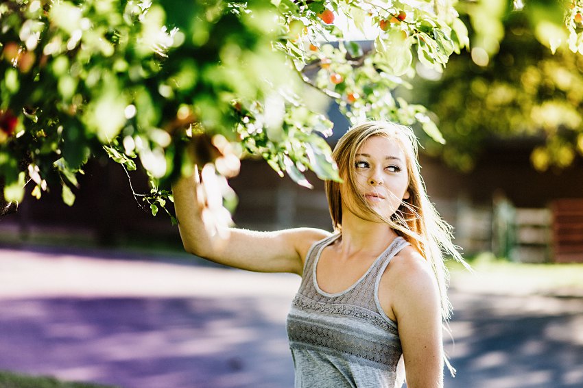 girl in a gray top standing under a crab apple tree
