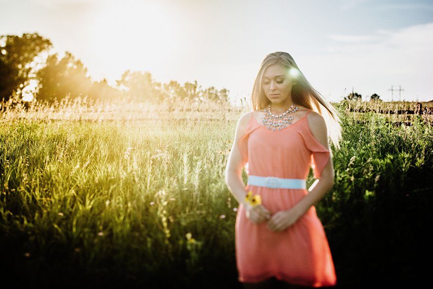 girl in a pink dress in a hazy sunset walking in tall grass