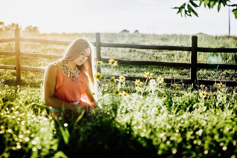 girl in a pink dress in a hazy sunset sitting in tall grass